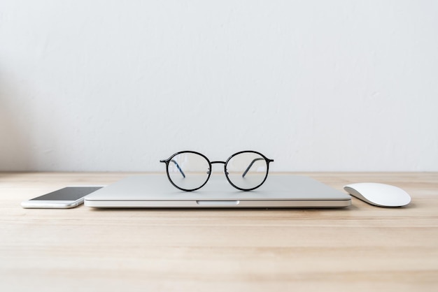 Składany laptop w miejscu pracy z okularami, smartfonem i myszą
