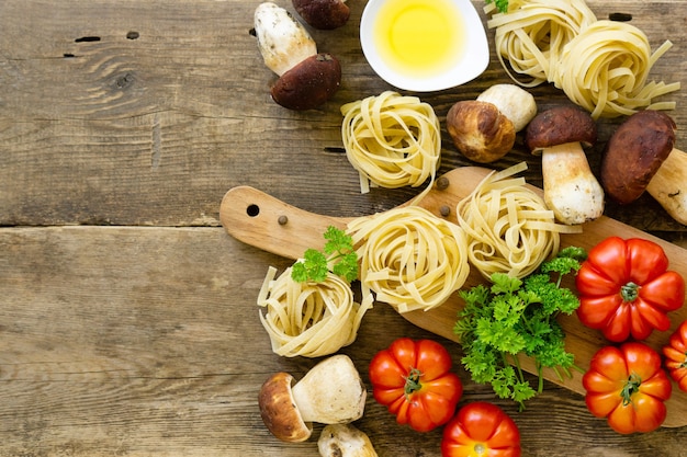 Składniki Do Gotowania Makaronu. Fettuccine Z Borowikami, Pomidorami I Zieleniną Na Starym Drewnianym Tle.