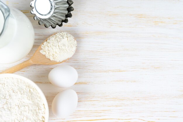 Składniki do pieczenia mąka jajka mleko do pieczenia na białym drewnianym tle z miejscem na kopię