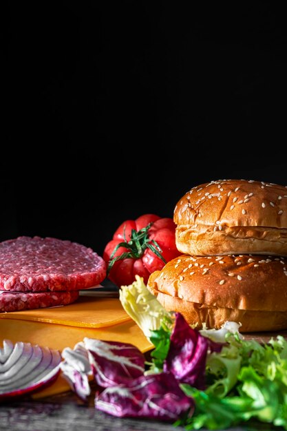Zdjęcie składniki do przygotowania hamburgera chleb świeży pomidor soczyste mięso chrupiąca cebula i zielona sałatka