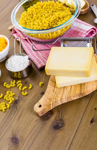 Składniki do przygotowania makaronu i sera na drewnianym stole.