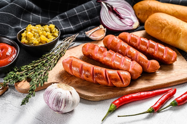 Składniki do robienia domowych hot-dogów. Kiełbaski, świeże bułeczki, musztarda, keczup, ogórki. Widok z góry