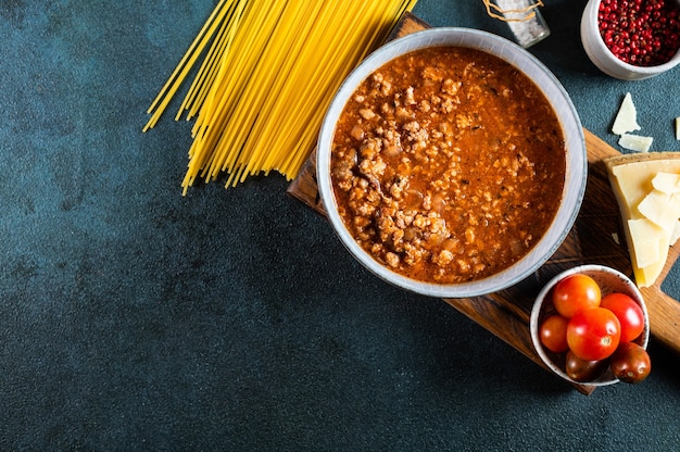 Składniki na spaghetti bolognese na ciemnym tle. Surowy makaron boloński. Makaron na płasko. Włoski bolończyk. Składniki żywności. Makaron widok z góry