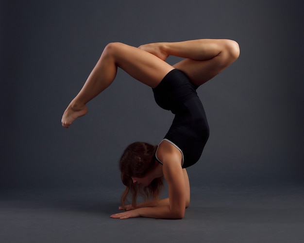 Skocz młoda kobieta robi ćwiczenia gimnastyczne na czarnym tle