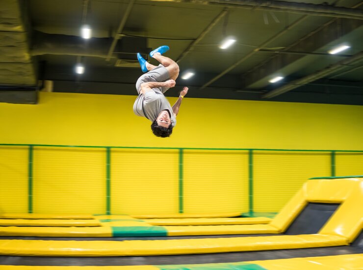 Zdjęcie skoczek na trampolinie wykonuje skomplikowane ćwiczenia akrobatyczne oraz salta na trampolinie.