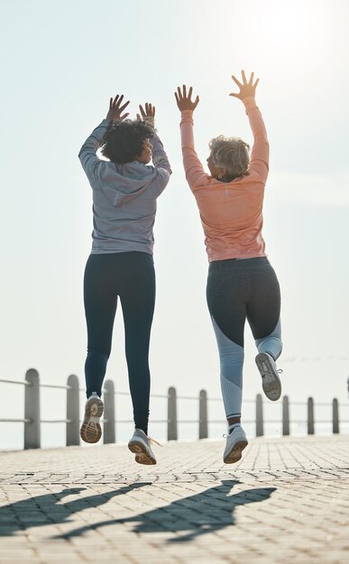 Skok fitness i sukces z przyjaciółmi na plaży w celu motywacji i treningu do świętowania Trening cardio i zdrowie z dojrzałymi kobietami w naturze w celu wspólnego biegania celów energetycznych i ćwiczeń