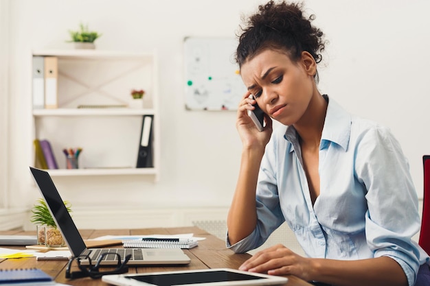 Skoncentrowana afro-amerykańska kobieta biznesu w pracy rozmawia przez telefon, siedzi w swoim miejscu pracy w biurze, kopia przestrzeń