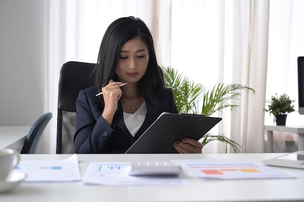 Skoncentrowana młoda bizneswoman analizująca dokument finansowy przy biurku