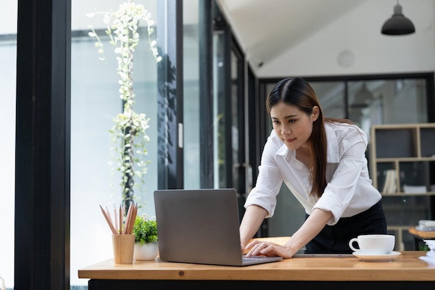 Skoncentrowana młoda kobieta biznesu pracująca na swoim komputerze Tło biura startowego