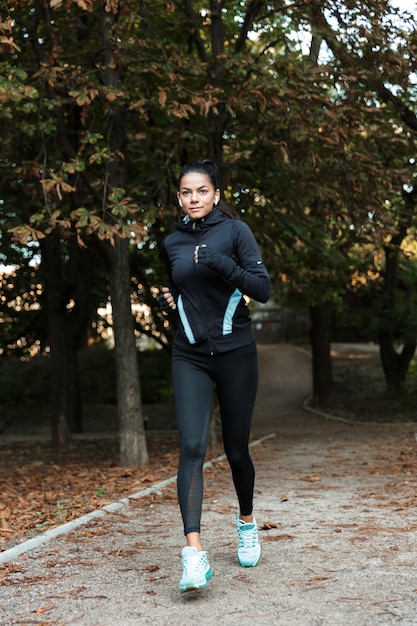 Skoncentrowana Młoda Kobieta Fitness Jogging W Parku, Słuchanie Muzyki Przez Słuchawki