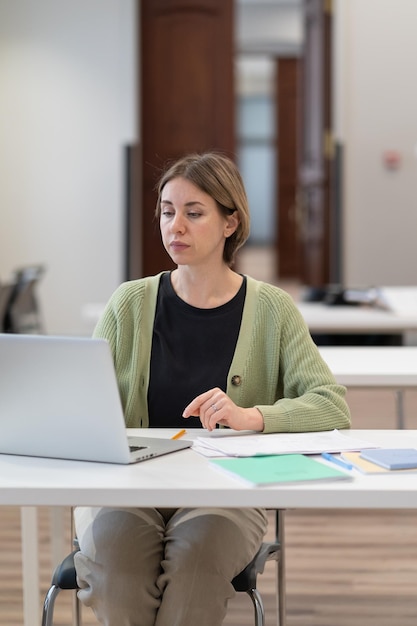 Skoncentrowana studentka w średnim wieku, pracująca na laptopie w przestrzeni coworkingowej, zdobywająca drugi stopień