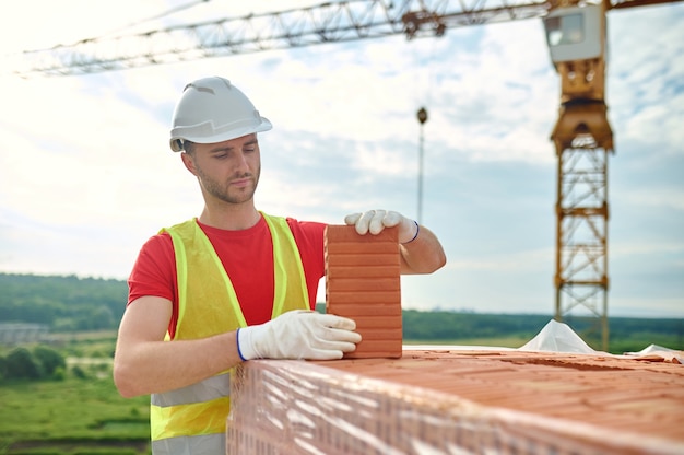 Zdjęcie skoncentrowany doświadczony konstruktor testujący perforowaną czerwoną cegłę