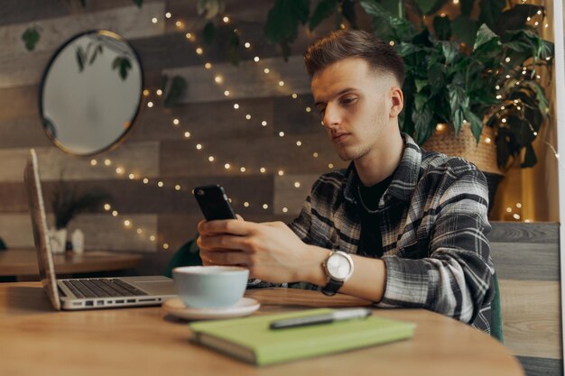 Zdjęcie skoncentrowany freelancer surfujący po internecie i przeglądający smartfon podczas pracy