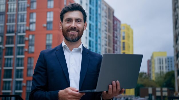 Skoncentrowany kaukaski biznesmen, pracownik po trzydziestce, pracuje jako niezależny poza biurem w mieście, korzysta z laptopa
