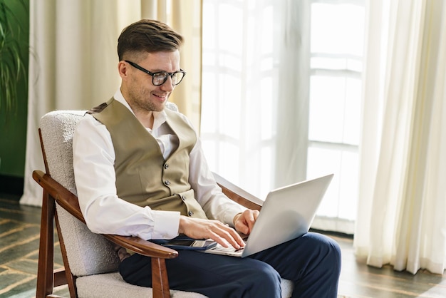Skoncentrowany mężczyzna w inteligentnej kamizelce używający laptopa w jasnym, powietrznym pokoju
