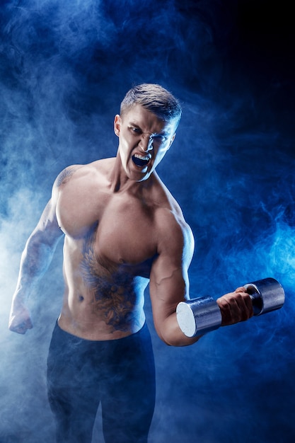 Skoncentrowany mięśniowy mężczyzna robi ćwiczeniu z dumbbell