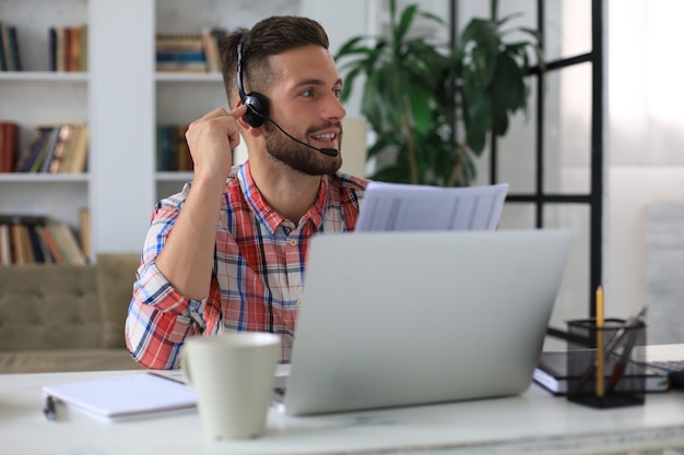 Skoncentrowany młody biznesmen freelancer za pomocą laptopa do wideokonferencji, pracujący zdalnie online w domu.