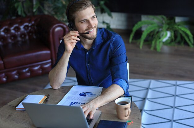 Skoncentrowany młody biznesmen freelancer za pomocą laptopa do wideokonferencji, pracujący zdalnie online w domu.