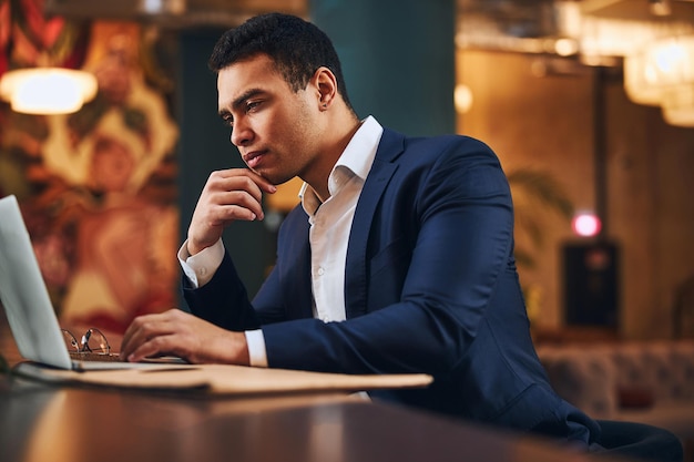 Skoncentrowany młody mężczyzna siedzący przed komputerem