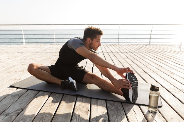 Skoncentrowany sportowiec na świeżym powietrzu na plaży sprawia, że ćwiczenia sportowe