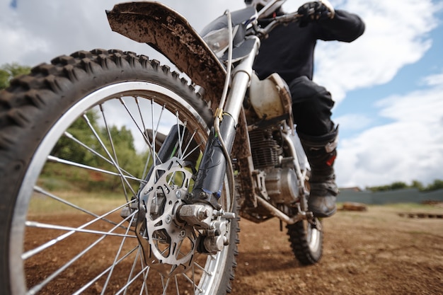 Skoncentruj się na kole brutalnego motocykla umieszczonego na torze terenowym, hobby lub koncepcji aktywności