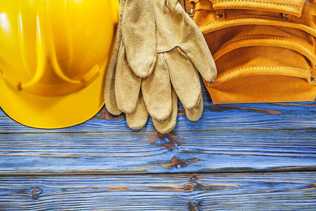 Zdjęcie skórzany pasek narzędziowy rękawice ochronne kask na niebieskiej drewnianej desce