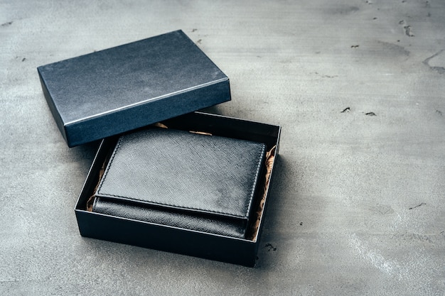 Skórzany portfel w pudełku na szarym betonowym tle