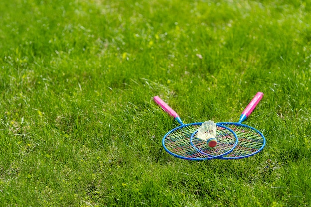 Zdjęcie skrzyżowane rakiety do badmintona z lotką nad nim na trawie