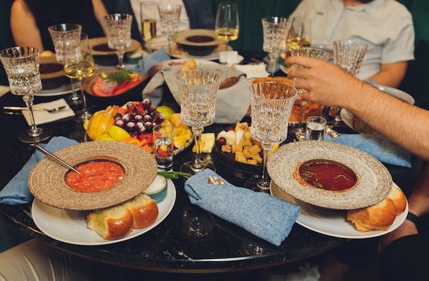 Skup się na rękach serwujących dania mięsno-warzywne grupie przyjaciół zgromadzonych wokół stołu na letnim tarasie