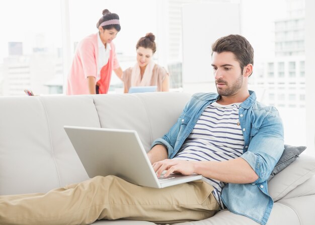 Skupiający się biznesmen używa laptop na kanapie