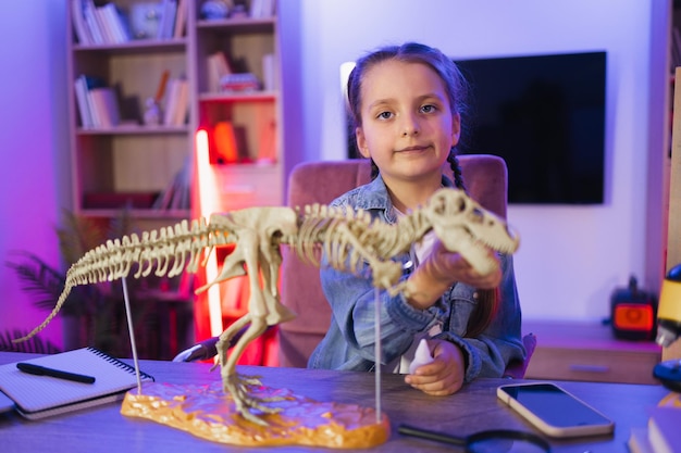 Skupiona dziewczynka robi model tyranozaura z kości.
