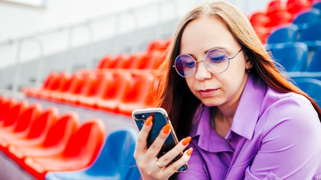 Skupiona kobieta korzystająca z telefonu komórkowego na trybunie