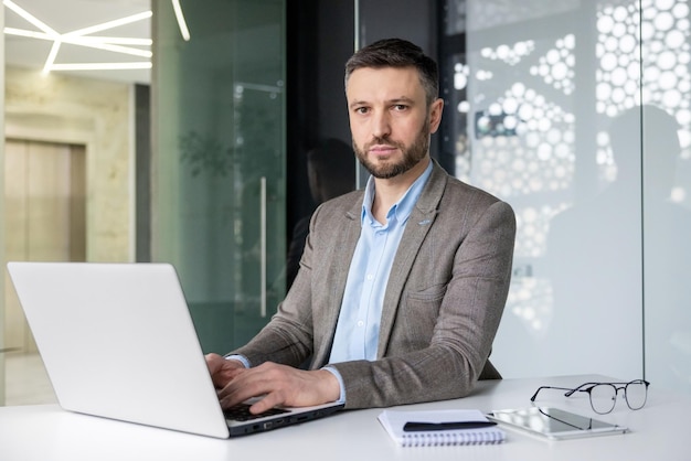 Skupiony biznesmen używający laptopa w stylowym, współczesnym środowisku biurowym.