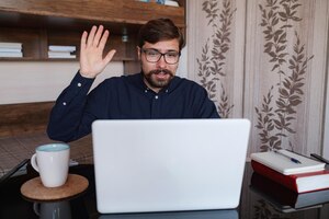 Zdjęcie skupiony mężczyzna siedzący przy biurku, oglądając kurs wideo z webinaru