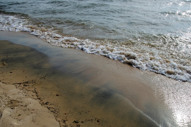 Ślady fal na piasku Fale obmywają piaszczystą plażę