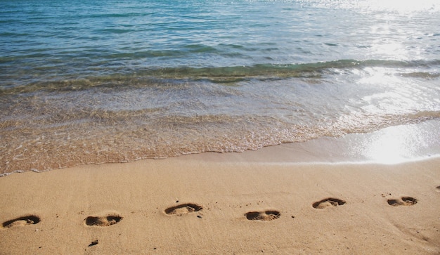 Zdjęcie Ślady na złotym piasku ślady na plaży w tle spokojna piękna fala oceanu na piaszczystej plaży morze vi