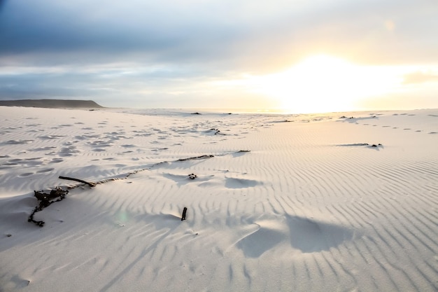 Ślady stóp na piasku na plaży o zachodzie słońca w Cape Town w RPA