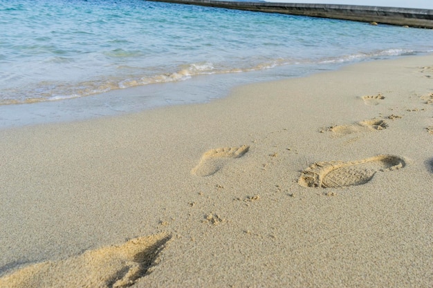 Ślady stóp na piasku plaży nad Morzem Śródziemnym na wyspie Ibiza w Hiszpanii, scena wakacyjna i letnia