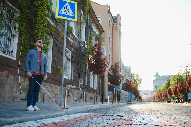 Ślepiec idący chodnikiem trzymający kij