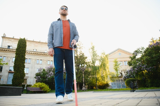 Ślepiec idący chodnikiem trzymający kij