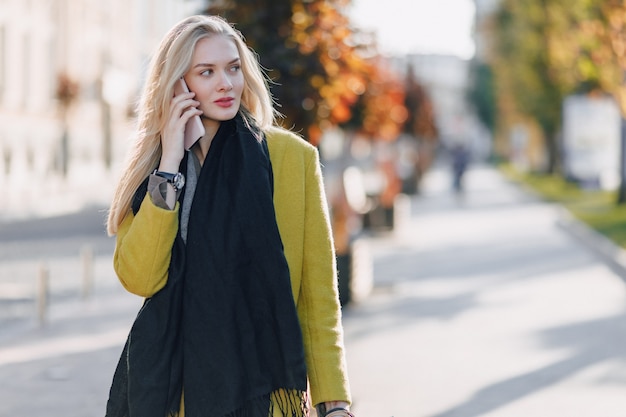 Śliczna Atrakcyjna Blondynki Kobieta Z Pakunkami Na Ulicie Przy Pogodną Pogodą. Komunikuje Się Przez Telefon Po Zakupach, Pozytywne Emocje.