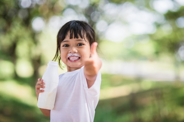 Śliczna azjatycka dziewczynka pije mleko, nieostrość