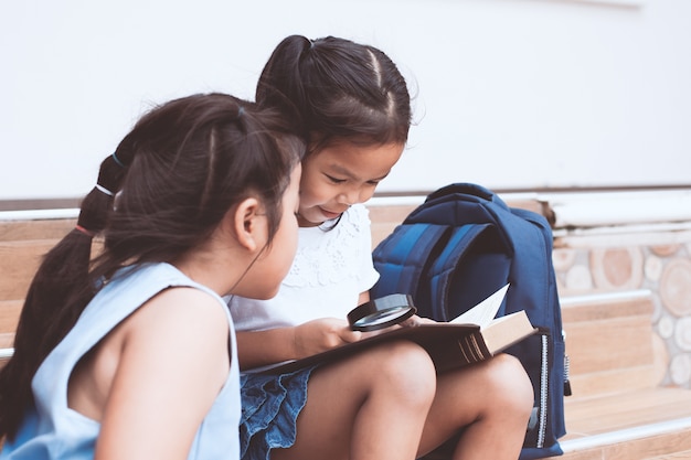 Śliczna azjatykcia dziecko dziewczyna i jej siostrzany czytanie książka wraz z zabawą i szczęściem