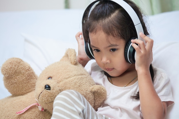 Śliczna azjatykcia dziecko dziewczyna słucha muzyka w hełmofonach