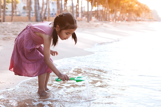 Śliczna azjatykcia małe dziecko dziewczyna ma zabawę bawić się na plaży w wakacje