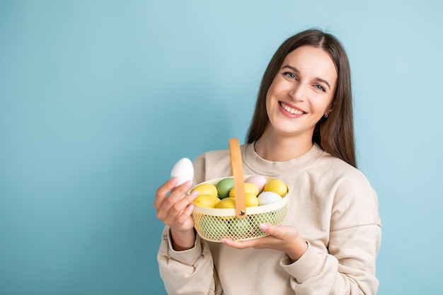 Śliczna brunetka trzyma w rękach malowane pisanki w koszyku Wielkanoc