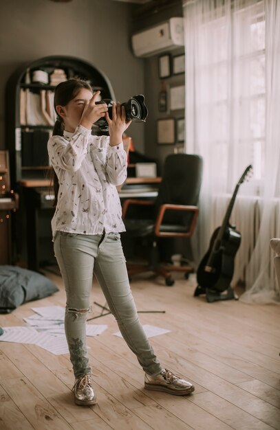 Śliczna brunetki mała dziewczynka trzyma fotografii kamerę w pokoju