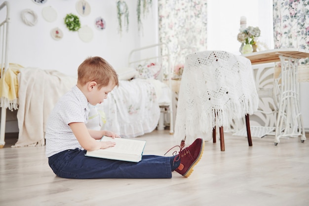 Śliczna chłopiec czyta książkę w domu