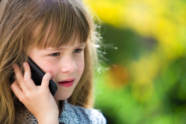 Śliczna Dziecko Młoda Dziewczyna Opowiada Na Telefonie Komórkowym Outdoors. Dzieci I Nowoczesna Technologia, Komunikacja.