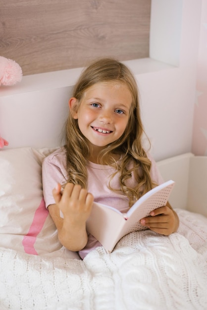 Śliczna dziewczyna czyta książkę leżącą w łóżku
